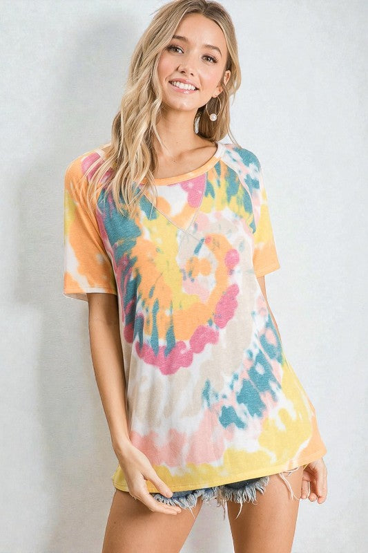Woman wearing a colorful tie-dye shirt against a plain background