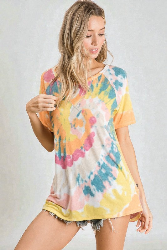 Woman wearing a colorful tie-dye shirt against a plain background