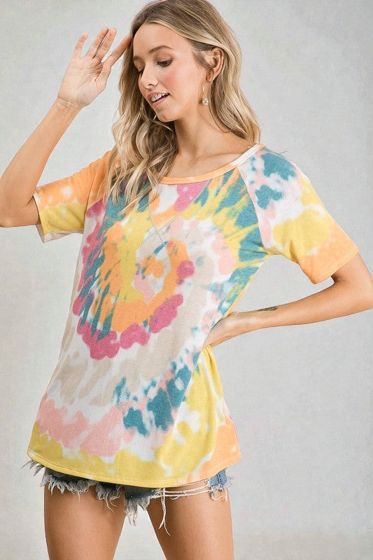 Woman wearing a colorful tie-dye shirt against a plain background