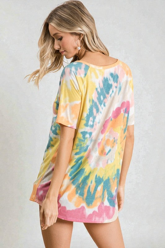 Woman wearing a colorful tie-dye dress against a plain background