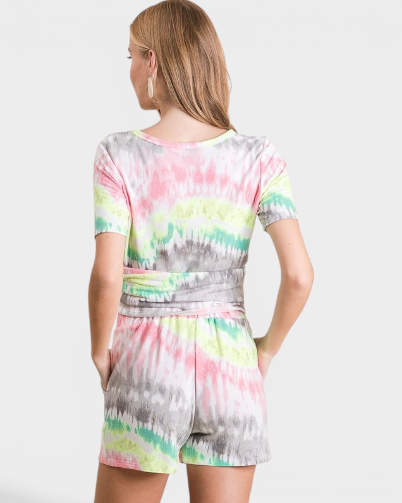 Woman wearing a colorful tie-dye romper on a white background