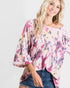 Woman wearing a colorful floral blouse with a plain background