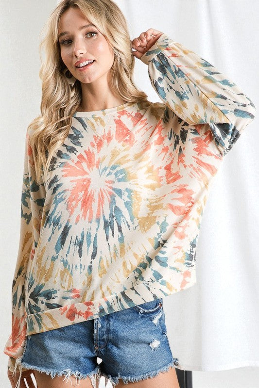 Woman wearing a tie-dye long-sleeve top and denim shorts on a white background