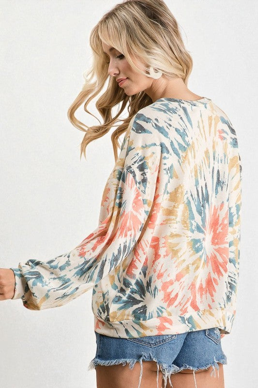 Woman wearing a tie-dye long-sleeve top with a white background
