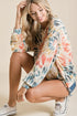 Woman wearing a colorful tie-dye shirt and shorts on a beige background