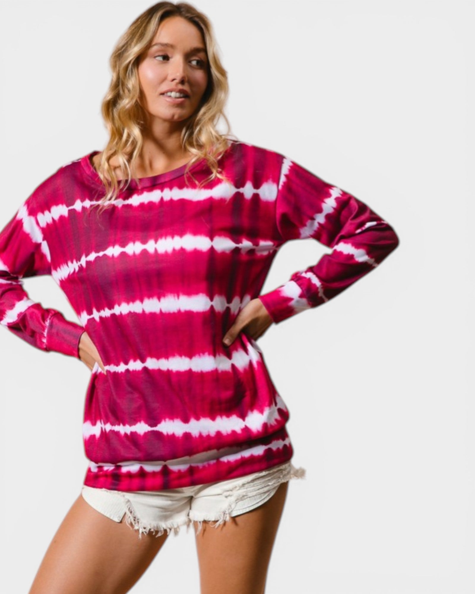 Woman wearing a pink and white tie-dye long-sleeve shirt on a plain background