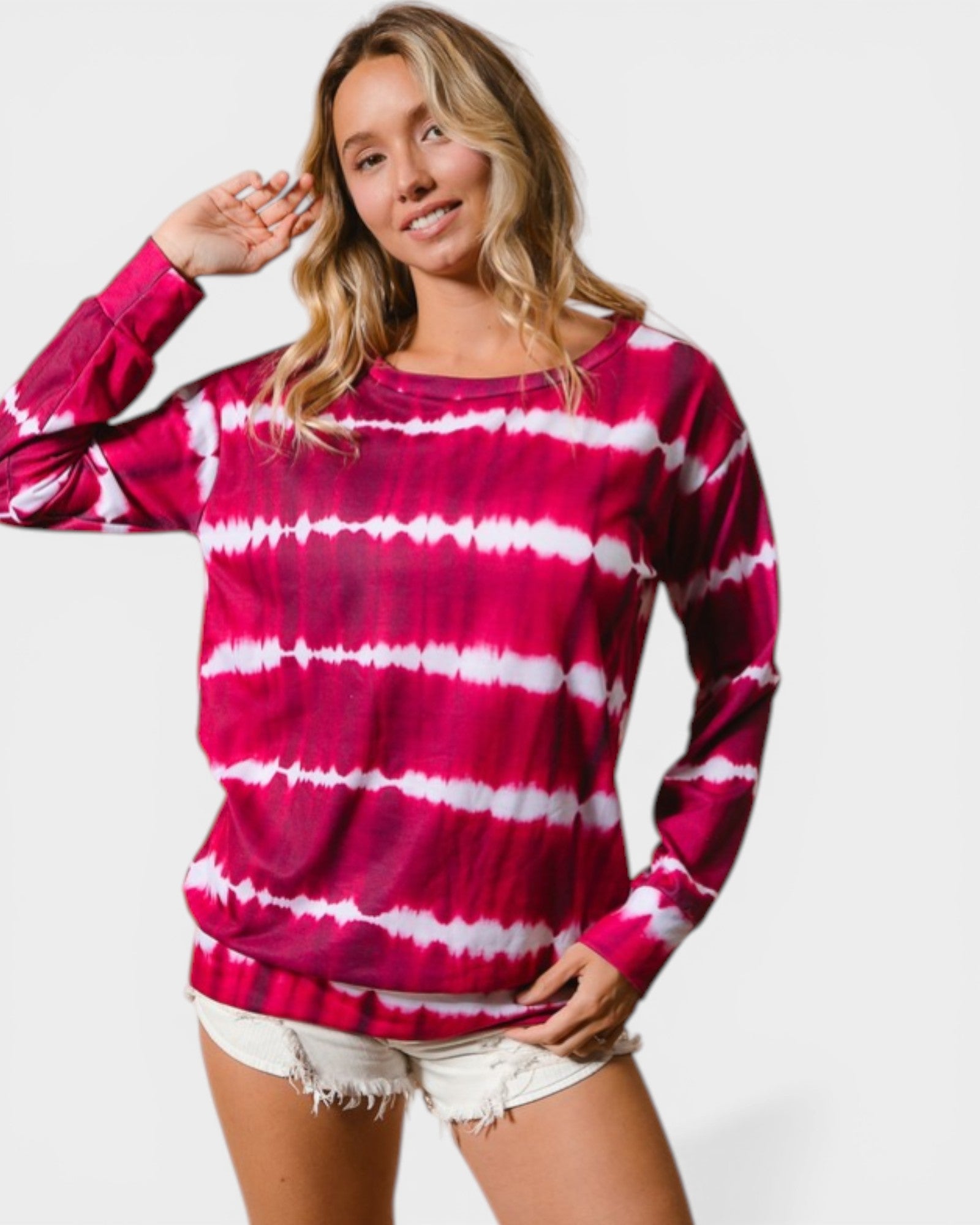 Woman wearing a pink and white tie-dye long-sleeve shirt on a plain background