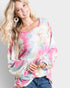 Woman wearing a colorful tie-dye long-sleeve shirt on a plain background