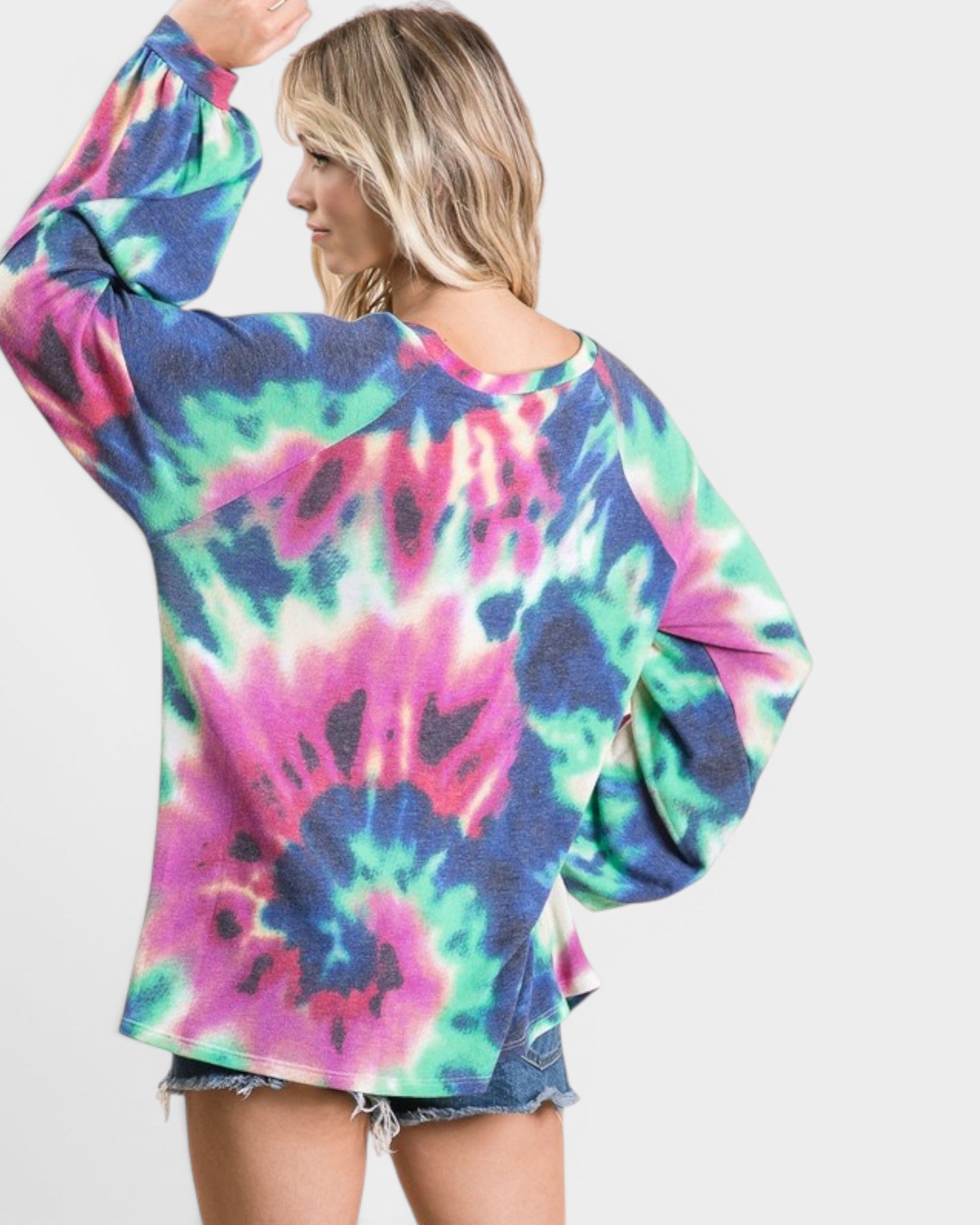 Person wearing a colorful tie-dye long-sleeve shirt on a white background