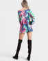 Person wearing a colorful tie-dye dress with black knee-high boots on a white background