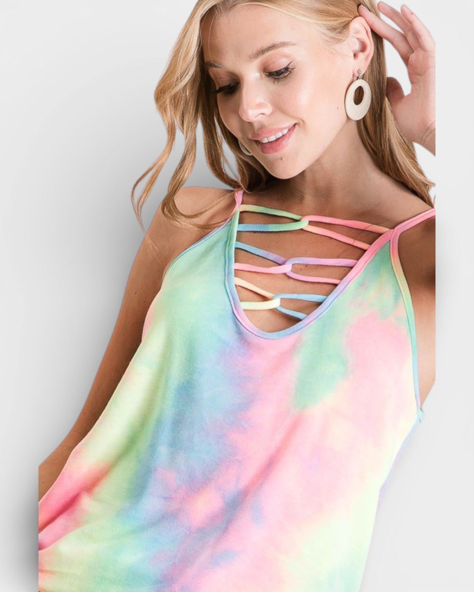 Woman wearing a colorful tie-dye tank top with strappy details on a plain background