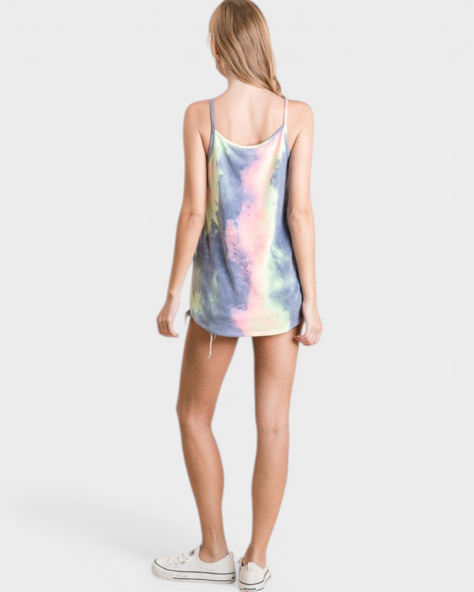 Woman wearing a tie-dye tank top on a plain background