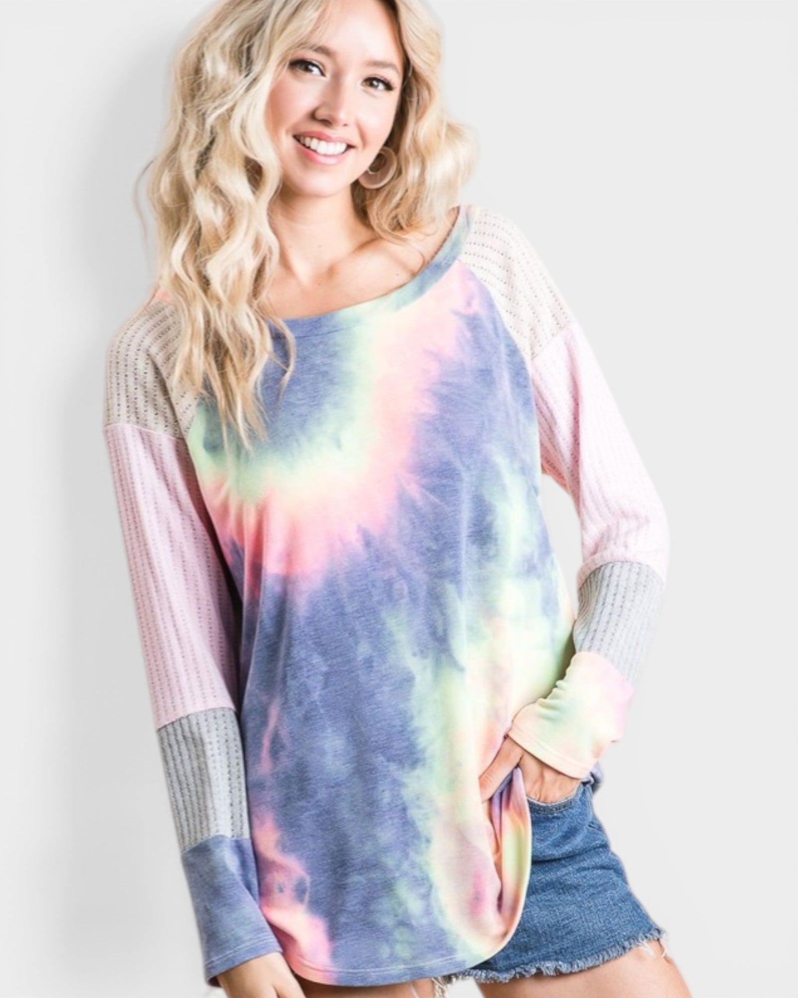 Woman wearing a tie-dye long-sleeve shirt with colorful patterns on a plain background