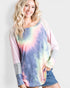 Woman wearing a tie-dye long-sleeve shirt with colorful patterns on a plain background
