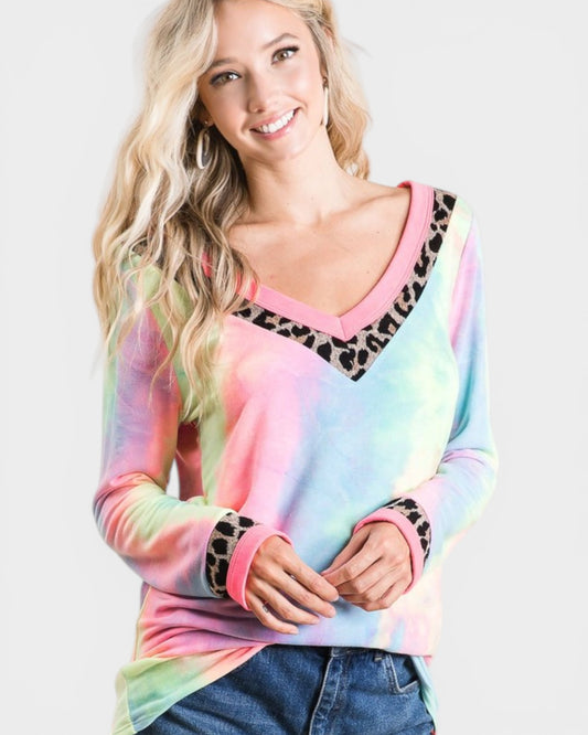 Woman wearing a colorful tie-dye long-sleeve shirt with leopard print accents on a white background