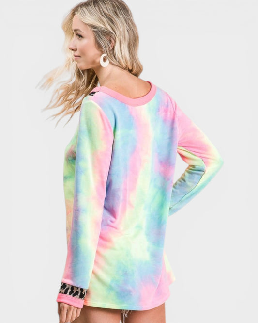 Woman wearing a colorful tie-dye long-sleeve shirt on a light gray background