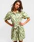 Woman wearing a green floral dress against a plain background
