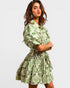 Woman wearing a green floral dress against a plain background
