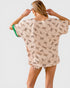 Woman wearing a beige cover-up with animal print on a plain background