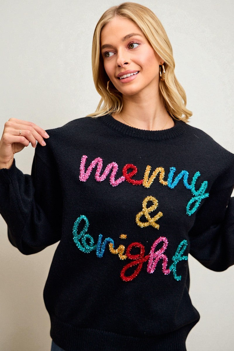Woman wearing a black sweater with colorful text on a plain background