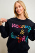 Woman wearing a black sweater with colorful text on a plain background