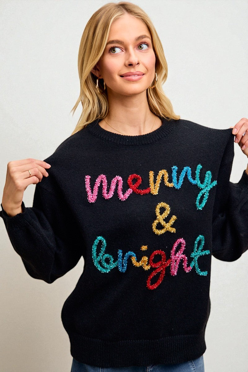 Woman wearing a black sweater with colorful text on a plain background