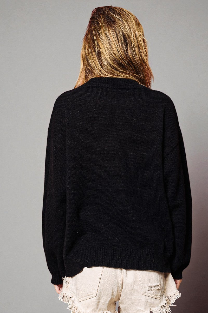 Person wearing a black sweater with a plain background