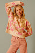 Woman wearing a floral sweater and pink pants against a neutral background