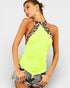 Woman wearing a neon green halter top with leopard print straps on a plain background