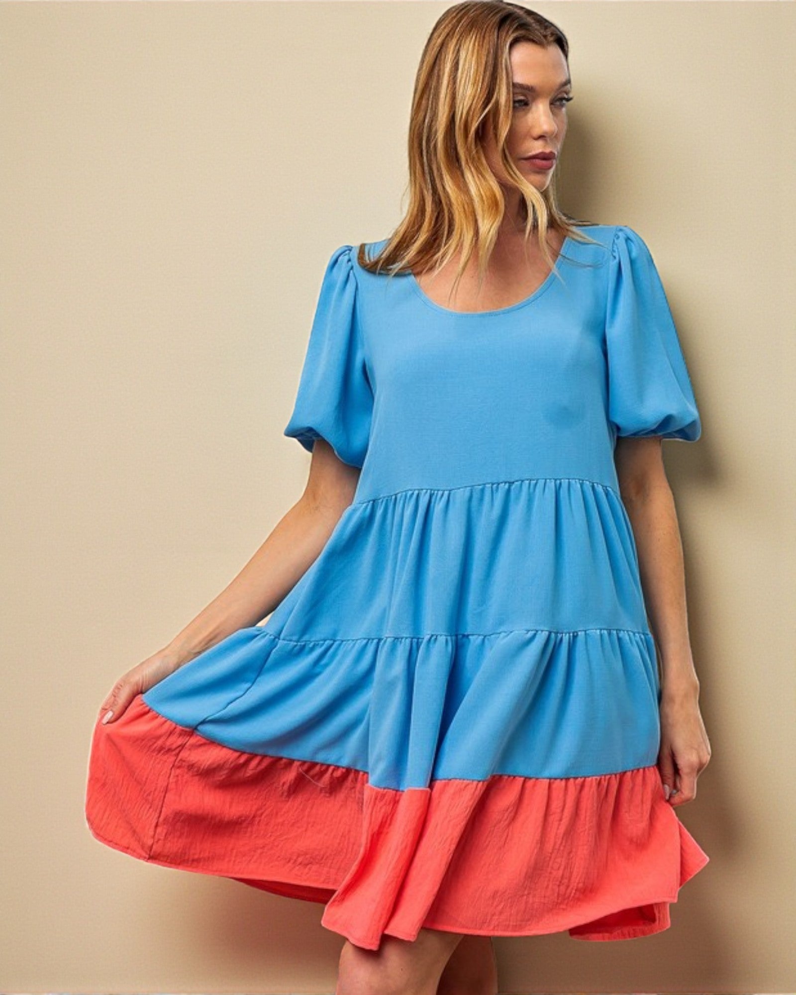 Woman wearing a blue and red dress against a beige background