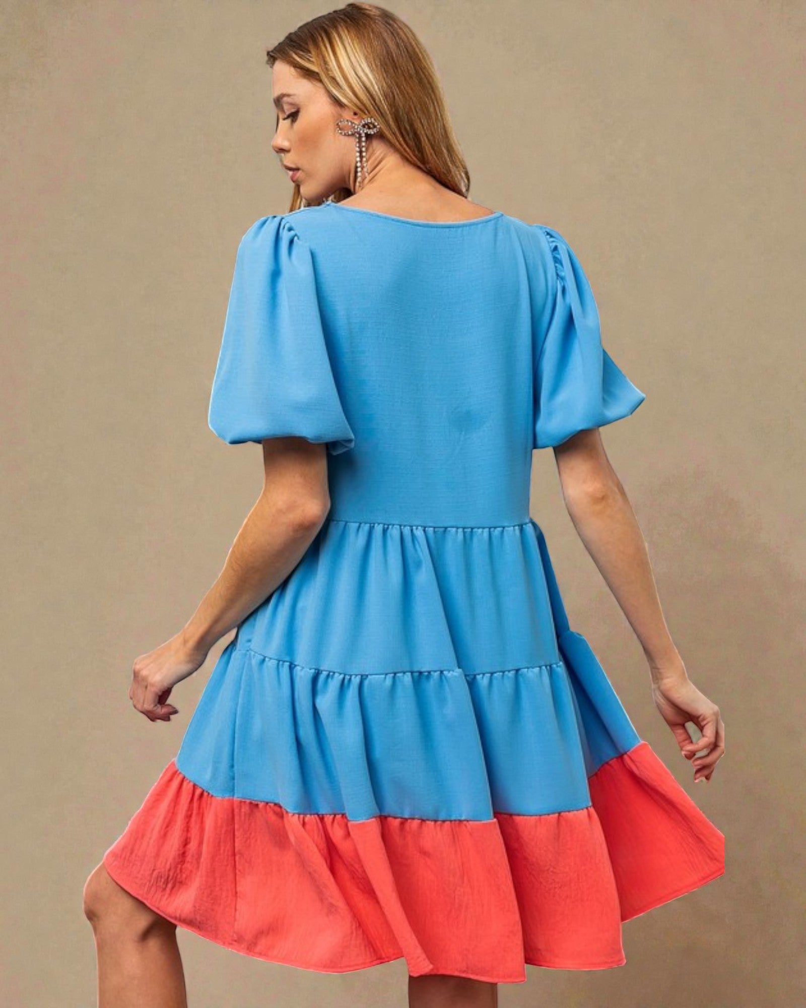 Woman wearing a blue and red dress against a beige background