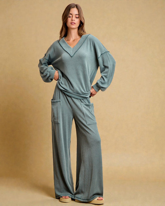 Woman wearing a teal lounge set against a beige background
