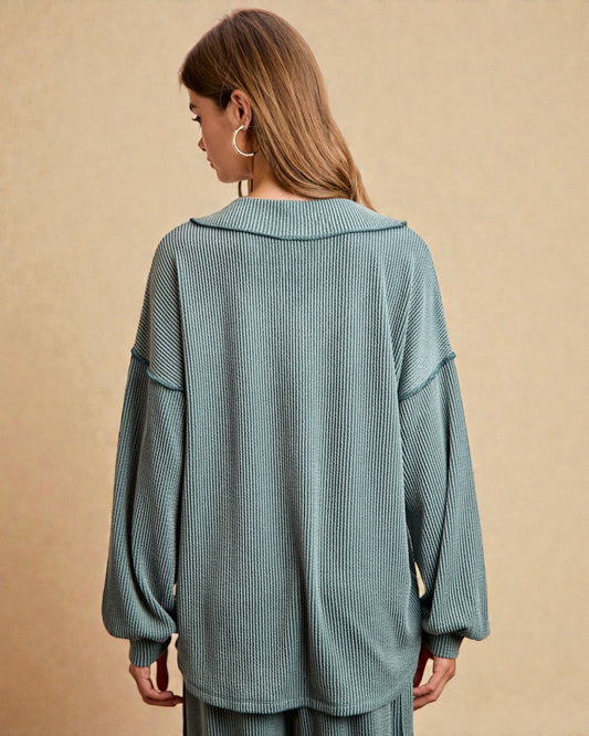 Woman wearing a teal ribbed sweater and pants on a beige background