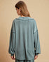 Woman wearing a teal ribbed sweater and pants on a beige background