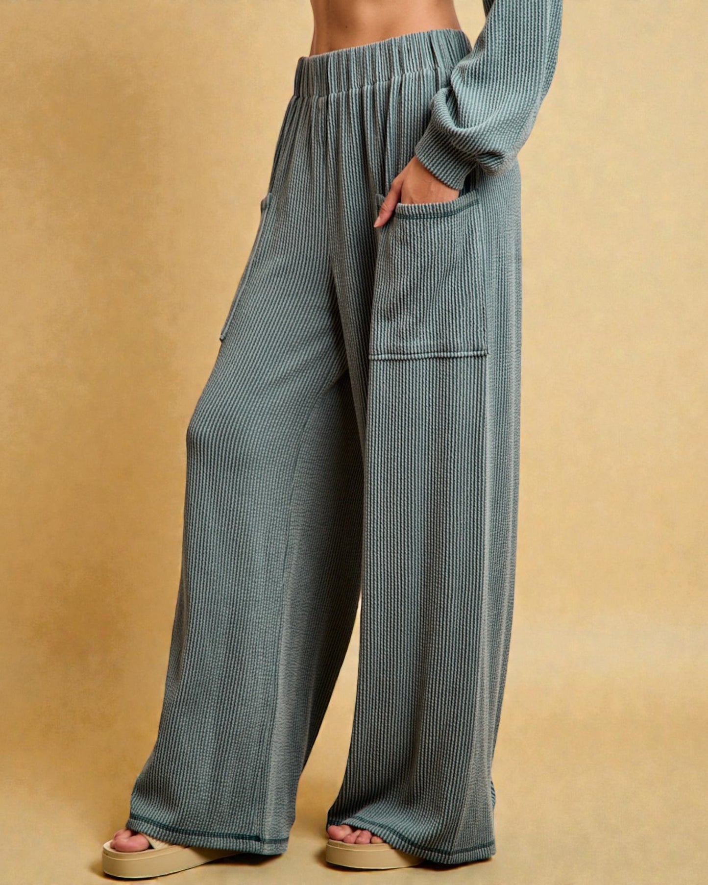Blue ribbed pants worn by a person on a beige background