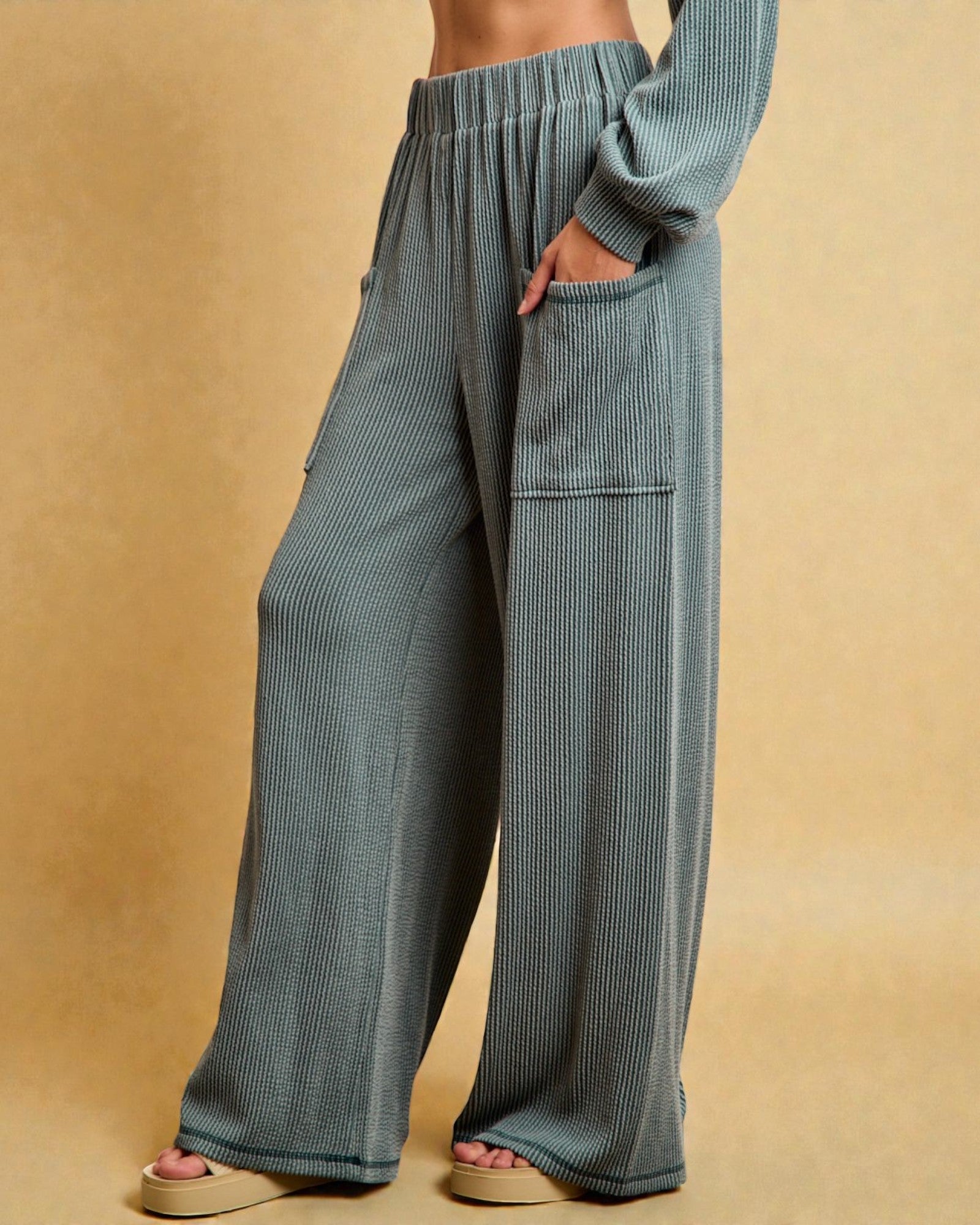 Blue ribbed pants worn by a person on a beige background