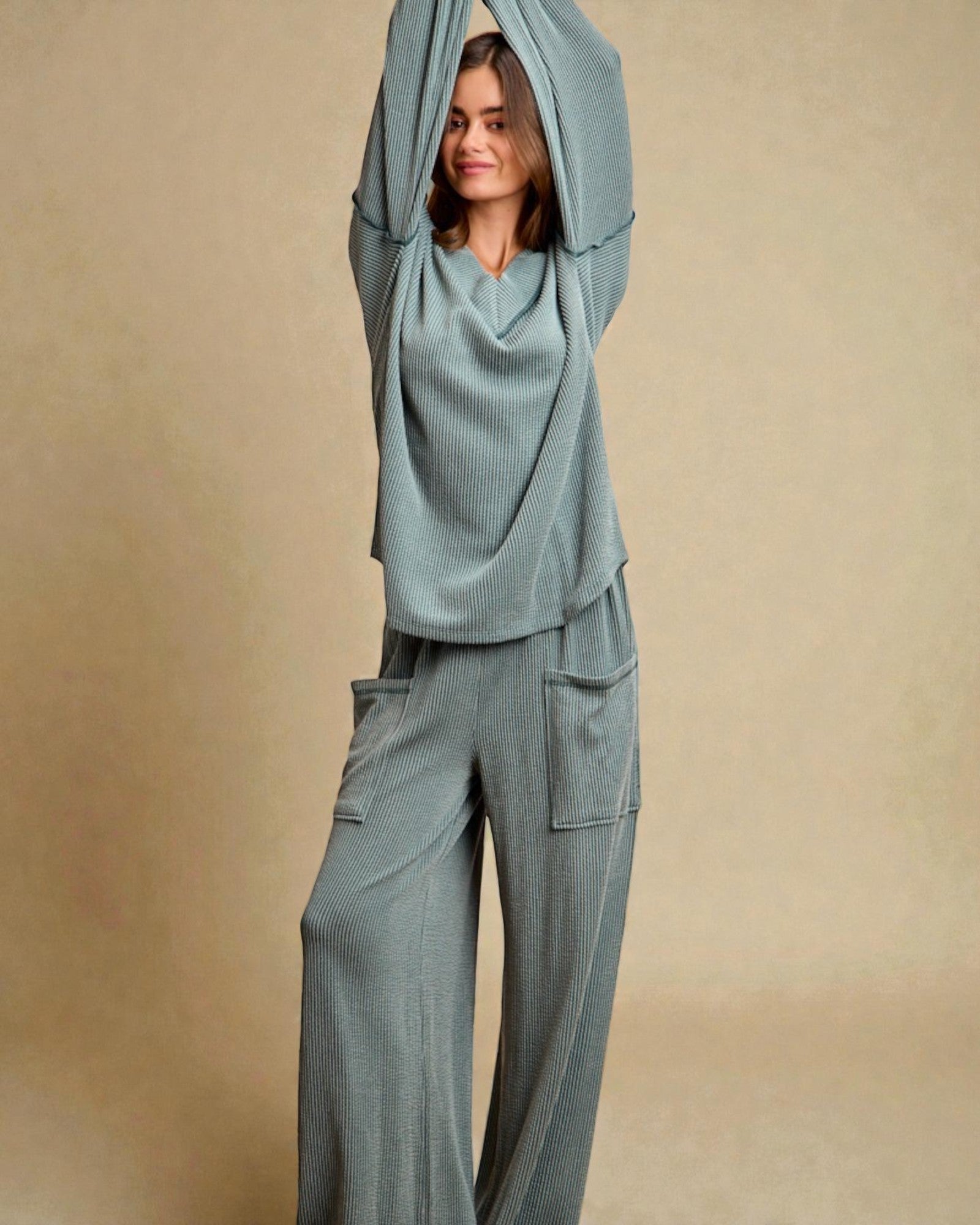 Woman wearing a teal outfit with a matching headscarf against a beige background