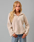Woman wearing a beige ribbed sweater with a zipper on a gray background