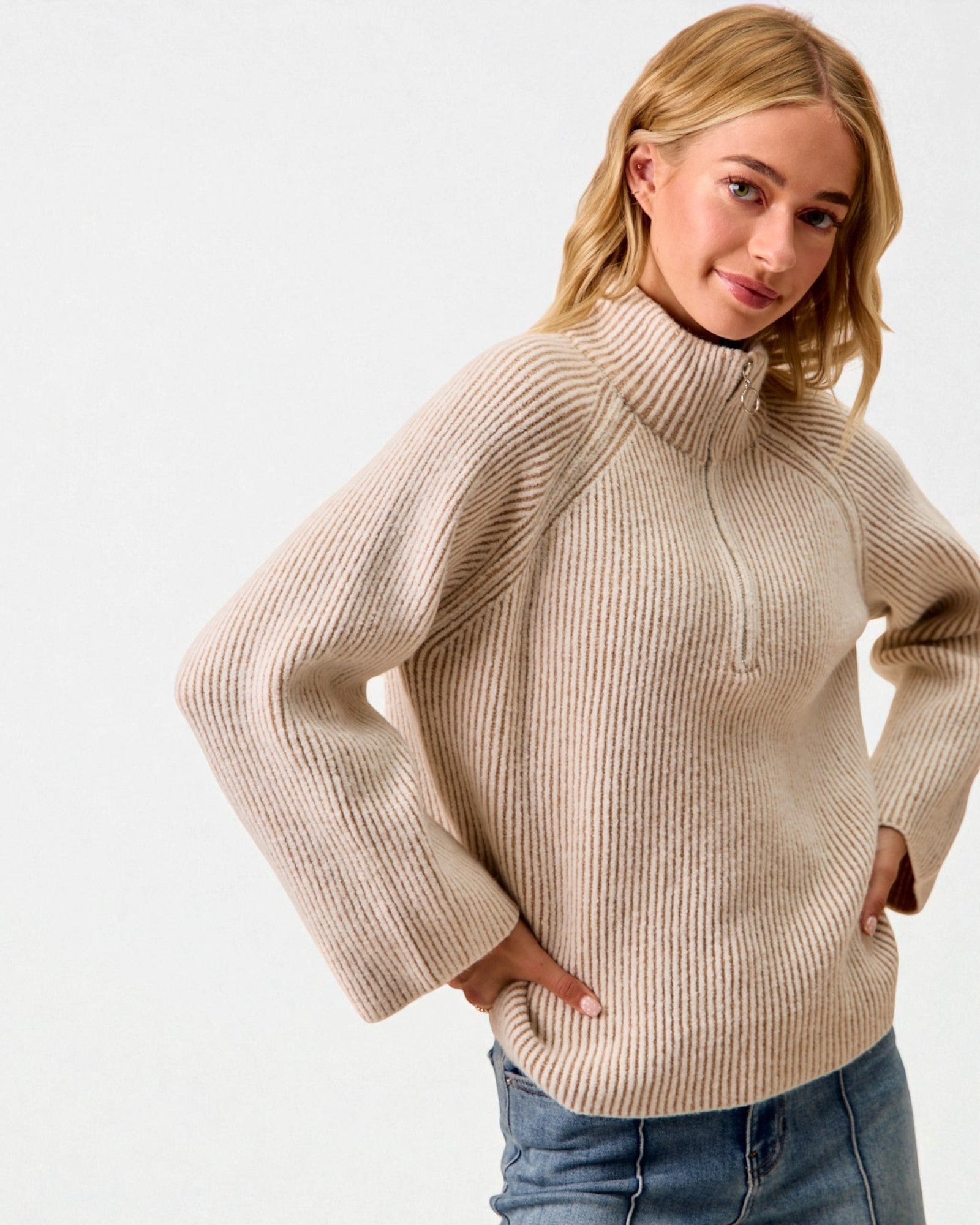 Woman wearing a beige sweater against a white background