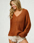 Woman wearing a brown knitted sweater and white shorts on a light background