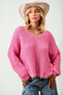 Woman wearing a pink chunky knit sweater and beige hat against a white background