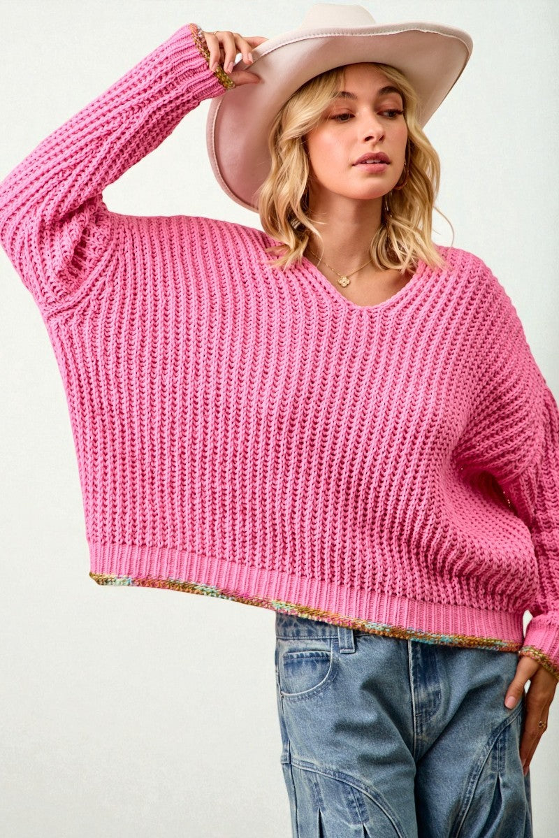 Woman wearing a pink sweater and wide-brimmed hat on a white background