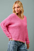Woman wearing a pink sweater against a gray background