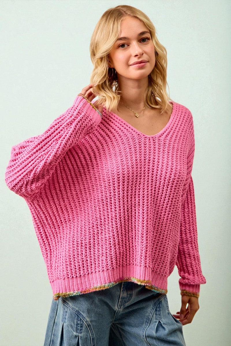 Woman wearing a pink chunky knit sweater against a light background