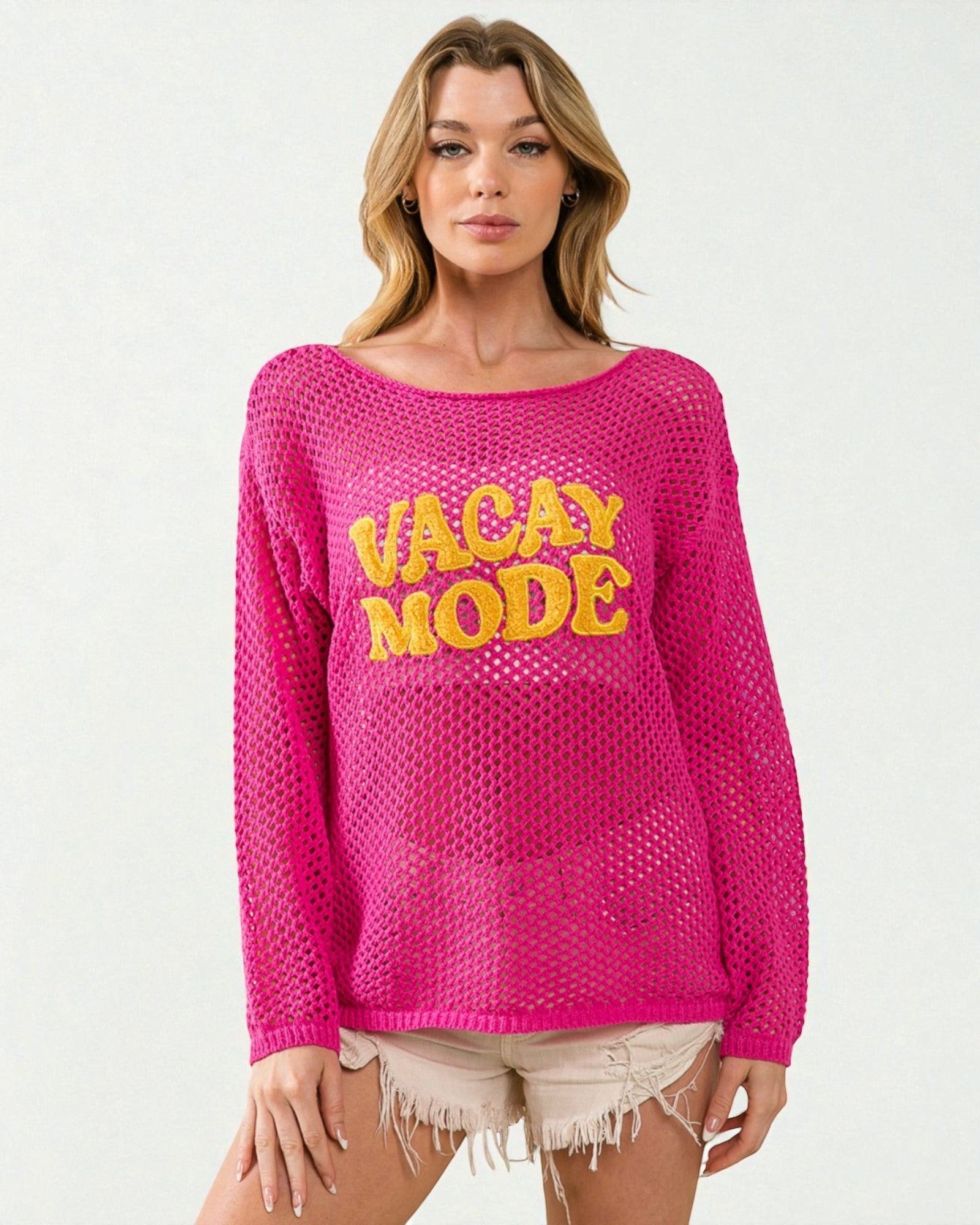 Woman wearing a pink sweater with 'Vacay Mode' text on a white background