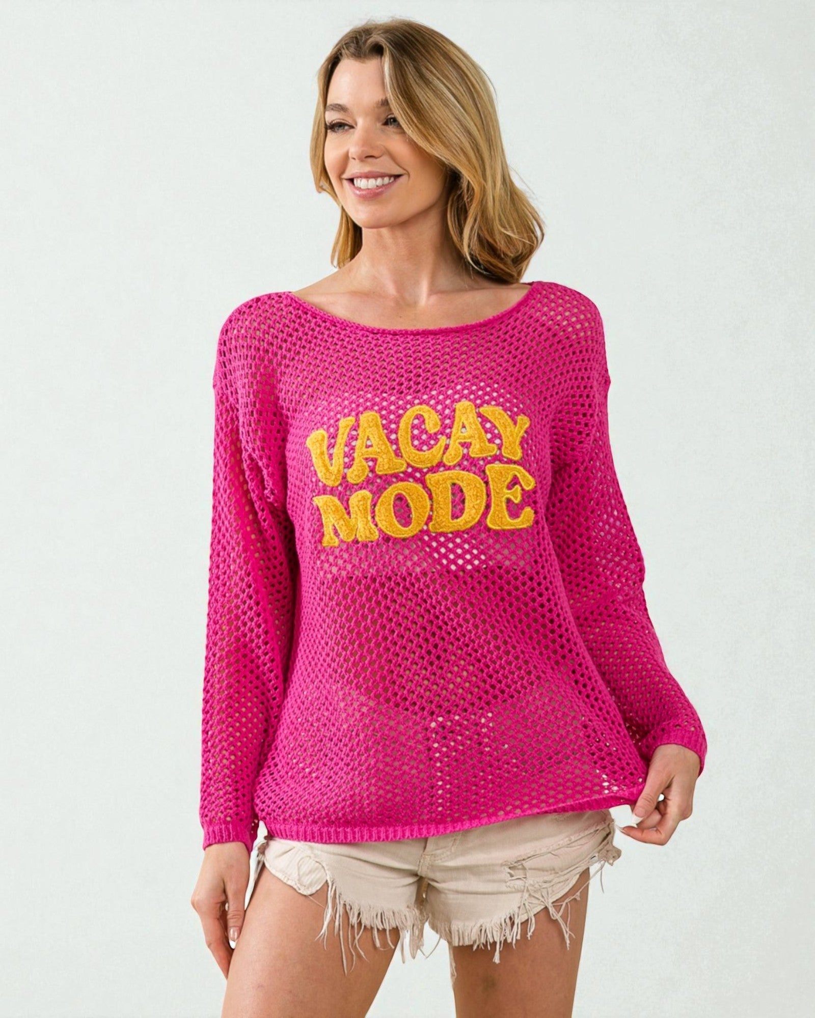 Woman wearing a pink sweater with 'VACAY MODE' text on a white background