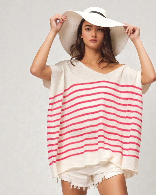 Woman wearing a white and red striped cover-up with a wide-brimmed hat on a plain background