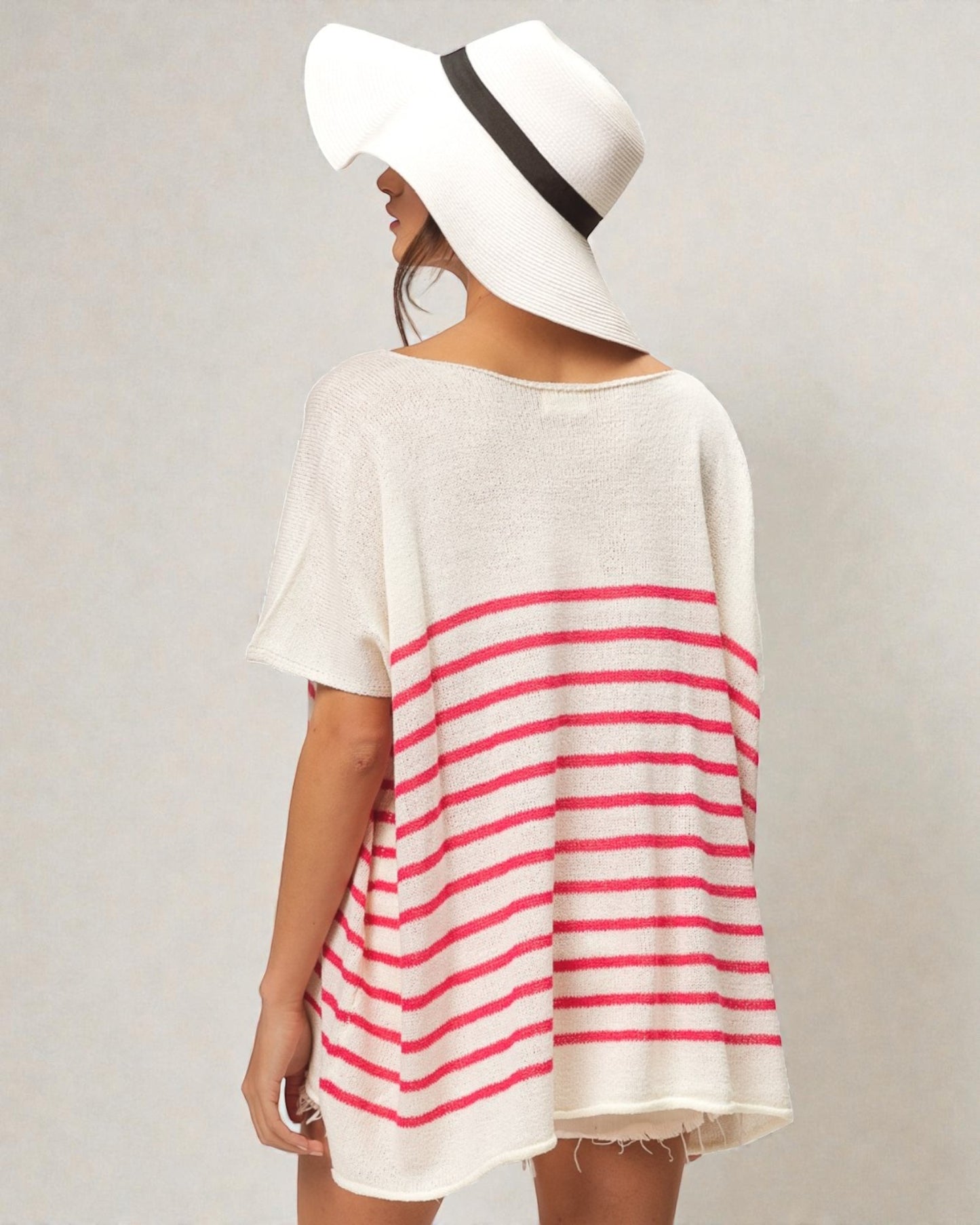 Person wearing a white and red striped dress with a wide-brimmed hat on a plain background