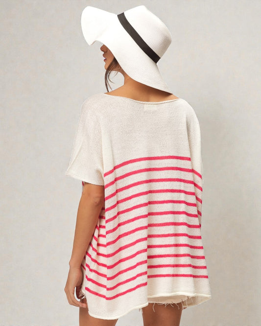 Person wearing a white and red striped dress with a wide-brimmed hat on a plain background