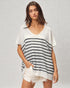 Woman wearing a white and navy striped t-shirt with white shorts on a light gray background